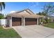 Single-story home with a two-car garage, showcasing a well-maintained lawn and landscaping and a white fence at 1862 Wood Bend St, Tarpon Springs, FL 34689