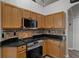 Well-lit kitchen features wooden cabinets, black countertops, and stainless steel appliances at 1862 Wood Bend St, Tarpon Springs, FL 34689