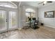 The office features wood-look floors, light gray walls, a ceiling fan, a large window, and glass-panel front doors at 22316 Red Jacket Ln, Land O Lakes, FL 34639