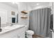 Well-lit bathroom with a single sink, wooden shelves and a shower-tub combo at 2572 Garden Plum Pl, Odessa, FL 33556