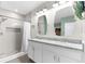 Modern bathroom with a double sink vanity, large mirrors, and tiled walk-in shower at 2572 Garden Plum Pl, Odessa, FL 33556