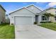 Home's exterior with an attached garage, manicured lawn, and mature landscaping at 2572 Garden Plum Pl, Odessa, FL 33556