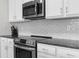Close-up of a kitchen featuring stainless steel oven and microwave, granite counters, and white tile backsplash at 2572 Garden Plum Pl, Odessa, FL 33556