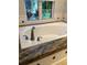 Bright white tub with granite surround and window at 2880 Chelsea N Pl, Clearwater, FL 33759
