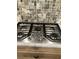 Gas cooktop with five burners set in granite countertop and stone backsplash at 2880 Chelsea N Pl, Clearwater, FL 33759