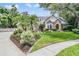 Charming stone and stucco home with lush landscaping, mature trees, and well-maintained lawn at 2880 Chelsea N Pl, Clearwater, FL 33759