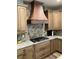 Gourmet kitchen with custom copper range hood, granite countertops and stone backsplash at 2880 Chelsea N Pl, Clearwater, FL 33759