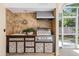 Stylish outdoor kitchen featuring a built-in grill, sink, tile backsplash and mosaic-patterned cabinetry at 2880 Chelsea N Pl, Clearwater, FL 33759