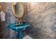 Stylish powder room showcasing a turquoise pedestal sink, round mirror, and textured walls at 2880 Chelsea N Pl, Clearwater, FL 33759
