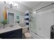 Bright bathroom featuring a shower-tub combination with modern white tile and a blue vanity at 2887 Cathy Ln, Clearwater, FL 33760