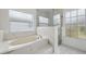 Bright bathroom showcasing a soaking tub, glass shower, and natural light from two windows at 3312 Blythe Ave, Spring Hill, FL 34609