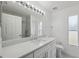 Bright bathroom featuring a large mirror, vanity, toilet, and window at 3312 Blythe Ave, Spring Hill, FL 34609