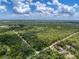 Wide aerial view showcasing the property's wooded acreage with dirt road and lake in the distance at 34335 Berryhill Dr, Webster, FL 33597