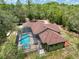 Aerial view showcasing a home with a screened-in pool, spacious yard, and treed boundary at 34335 Berryhill Dr, Webster, FL 33597