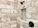 A well-lit walk-in shower featuring decorative tiled walls, with a recessed shower niche at 34335 Berryhill Dr, Webster, FL 33597