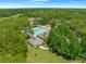 Aerial view showcases a sparkling pool, pool house, and recreation area nestled among lush green trees at 3900 Autumn Amber Dr, Spring Hill, FL 34609