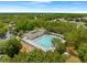 Aerial view of large community pool, playground, and surrounding neighborhood with lush trees and blue skies at 3900 Autumn Amber Dr, Spring Hill, FL 34609