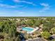 Aerial view of a community pool surrounded by trees and homes in the distance under a clear blue sky at 3900 Autumn Amber Dr, Spring Hill, FL 34609