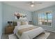 Comfortable bedroom with pastel blue walls, ceiling fan, and a bright sunny window at 4125 Mc Clung Dr, New Port Richey, FL 34653