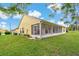 Exterior view showcasing the backyard, screened in patio, and vibrant green lawn at 4125 Mc Clung Dr, New Port Richey, FL 34653