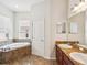 Bright bathroom featuring a soaking tub, double vanity, and tile floors at 4266 High Ridge Ave, Spring Hill, FL 34609