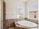Close up on a soaking tub with brown tiling, surrounded by two sunny windows at 4266 High Ridge Ave, Spring Hill, FL 34609