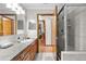 Modern bathroom with a glass-door shower, wood cabinets, gray counter, and decorative light fixture at 4289 Castle Ave, Spring Hill, FL 34609