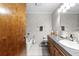 Well-lit bathroom featuring a tub, tiled walls, gray countertop, and wood cabinetry at 4289 Castle Ave, Spring Hill, FL 34609