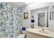 This bright bathroom features a white vanity, blue floral shower curtain, and modern fixtures at 4557 Glen Holw, New Port Richey, FL 34653