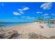Beautiful sandy beach with calm water, palm trees, beach chairs and picnic gazebos under a sunny sky at 4939 Floramar Ter # 611, New Port Richey, FL 34652