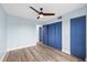 A bedroom features stylish wood-look floors, ample closet space with blue doors, and a modern ceiling fan at 4939 Floramar Ter # 611, New Port Richey, FL 34652