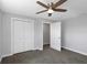 A well-lit bedroom features a ceiling fan, neutral paint, soft gray carpeting, and a double closet with doors at 5145 Porpoise Pl, New Port Richey, FL 34652