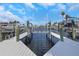 View of a private boat dock with boat lift overlooking the waterway, with palm trees and a blue sky at 5145 Porpoise Pl, New Port Richey, FL 34652