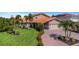 Beautiful single-Gathering home with lush green lawn, mature palm trees, a terracotta tile roof, and brick paver driveway at 5145 Porpoise Pl, New Port Richey, FL 34652