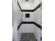 Modern shower with sleek white tiles, dark accent stripes, and a built-in niche for storage and grey tiled floors at 5145 Porpoise Pl, New Port Richey, FL 34652