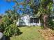 Charming white cottage with a screened porch and lush landscaping, nestled under mature trees at 5625 Van Doren Ave, New Port Richey, FL 34652