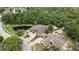 Aerial view of a brick home and a large backyard pond amid lush greenery and well-manicured landscaping at 5747 Fieldspring Ave, New Port Richey, FL 34655