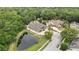A high-angle, eye-level shot showcases a spacious yard with pond, mature trees, and the home's roof and driveway at 5747 Fieldspring Ave, New Port Richey, FL 34655