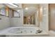 Spacious bathroom with large jacuzzi tub, glass-enclosed shower, decorative wall mirror, and neutral tile at 5747 Fieldspring Ave, New Port Richey, FL 34655