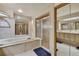Bright bathroom features a large tub, glass-enclosed shower, double vanity, large mirrors, and tile flooring at 5747 Fieldspring Ave, New Port Richey, FL 34655
