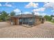 Brick exterior showcasing a charming design, a large brick-paved driveway, and lush landscaping under a partly cloudy sky at 5747 Fieldspring Ave, New Port Richey, FL 34655