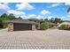 Brick home with a paver driveway, manicured landscaping with bushes and palm trees offering curb appeal, and a two-car garage at 5747 Fieldspring Ave, New Port Richey, FL 34655