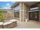 Charming brick home entrance featuring a decorative stone wall and a dark wood front door with glass accents at 5747 Fieldspring Ave, New Port Richey, FL 34655