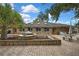 The home features a brick exterior, a well-manicured front yard with a fountain, and a spacious brick-paved area for parking at 5747 Fieldspring Ave, New Port Richey, FL 34655