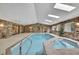 Inviting indoor pool and jacuzzi featuring brick surround, skylights, and ample seating at 5747 Fieldspring Ave, New Port Richey, FL 34655