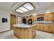 Open-concept kitchen with an island, oak cabinetry, granite counter, and modern appliances at 5747 Fieldspring Ave, New Port Richey, FL 34655