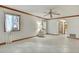 Open living room with white tile, ceiling fan, two windows with curtains, and an arched entryway at 5747 Fieldspring Ave, New Port Richey, FL 34655