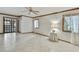 Bright, open living room with white tile, ceiling fan, sliding glass doors, and two windows with white curtains at 5747 Fieldspring Ave, New Port Richey, FL 34655
