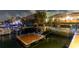 Night view of the private dock featuring wood platform with waterfront homes and lush tropical foliage at 6601 Nautical Isle, Hudson, FL 34667