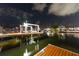 Night view of the private boat dock featuring a boat lift with calm water reflecting city lights at 6601 Nautical Isle, Hudson, FL 34667